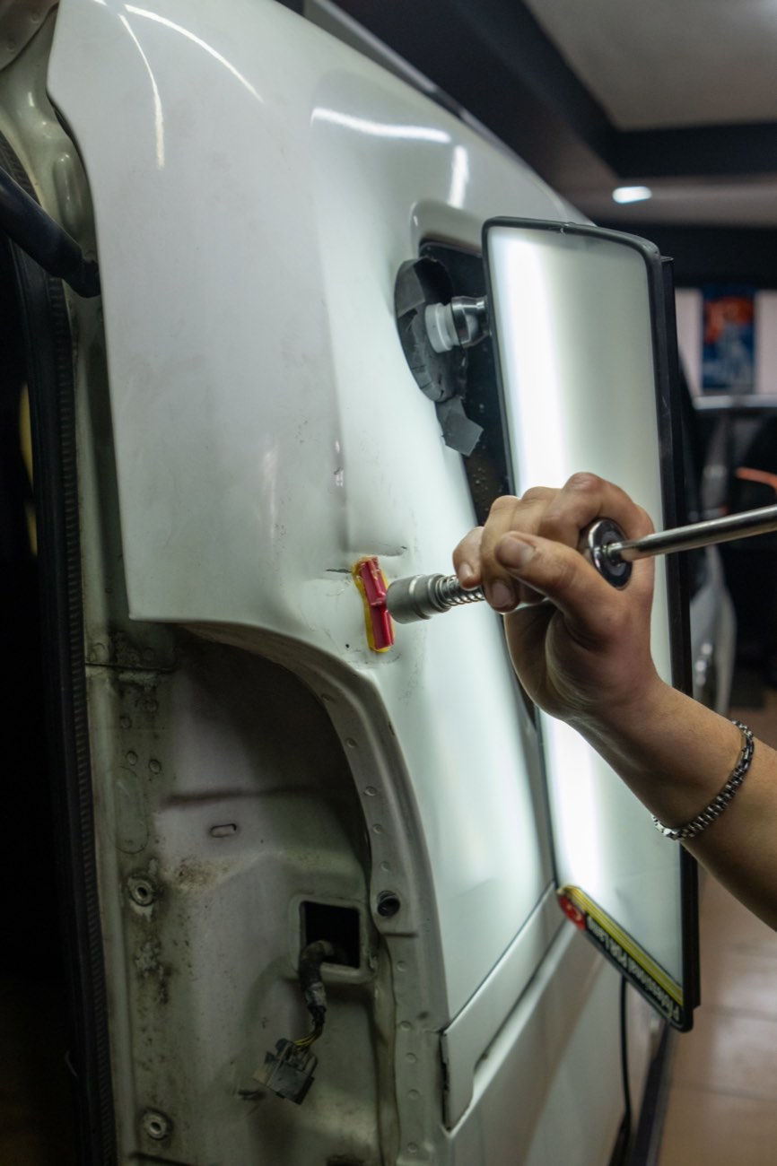 Técnico reparando una abolladura en la puerta de un vehículo